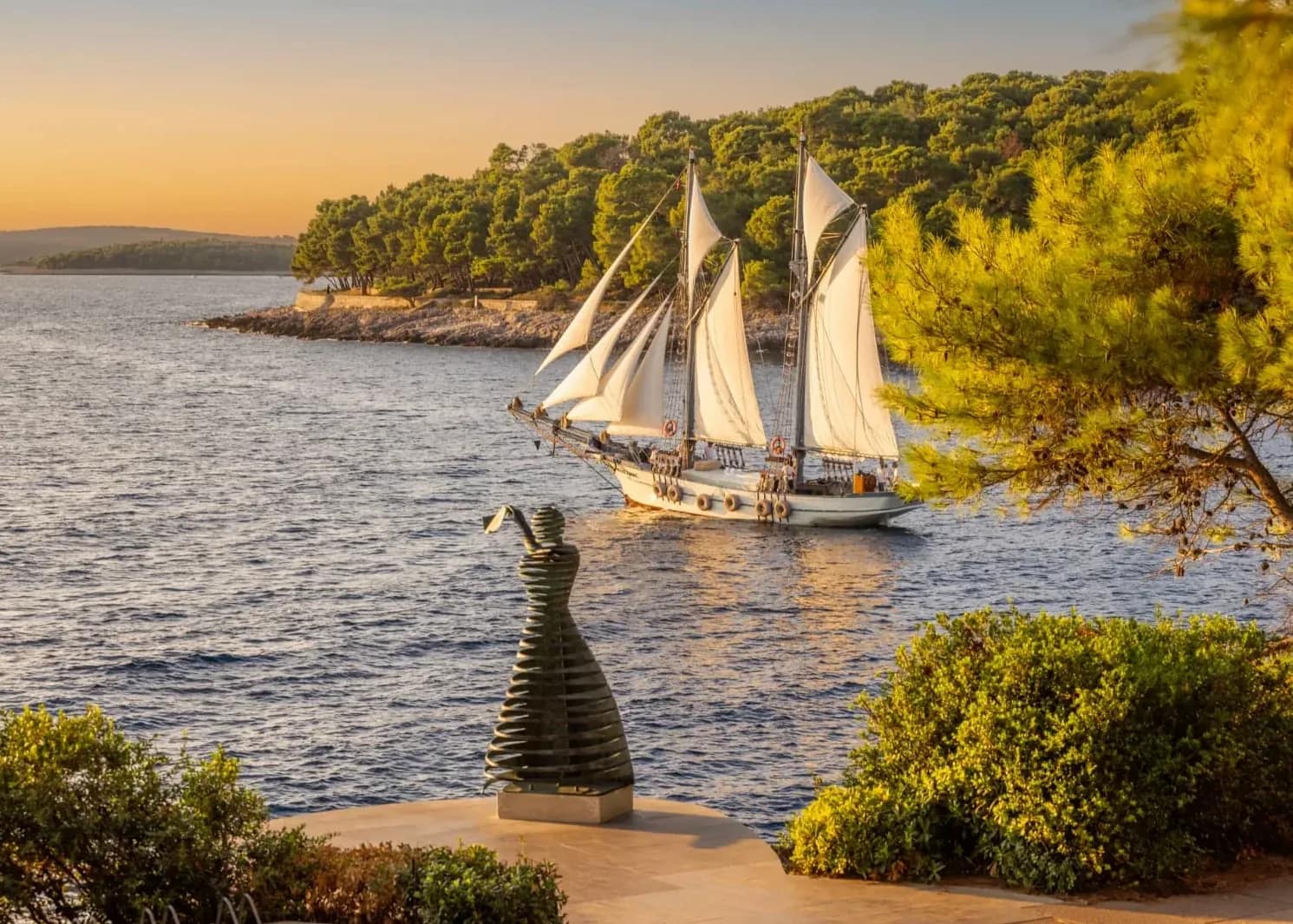 A historic schooner passing the shore at golden hour