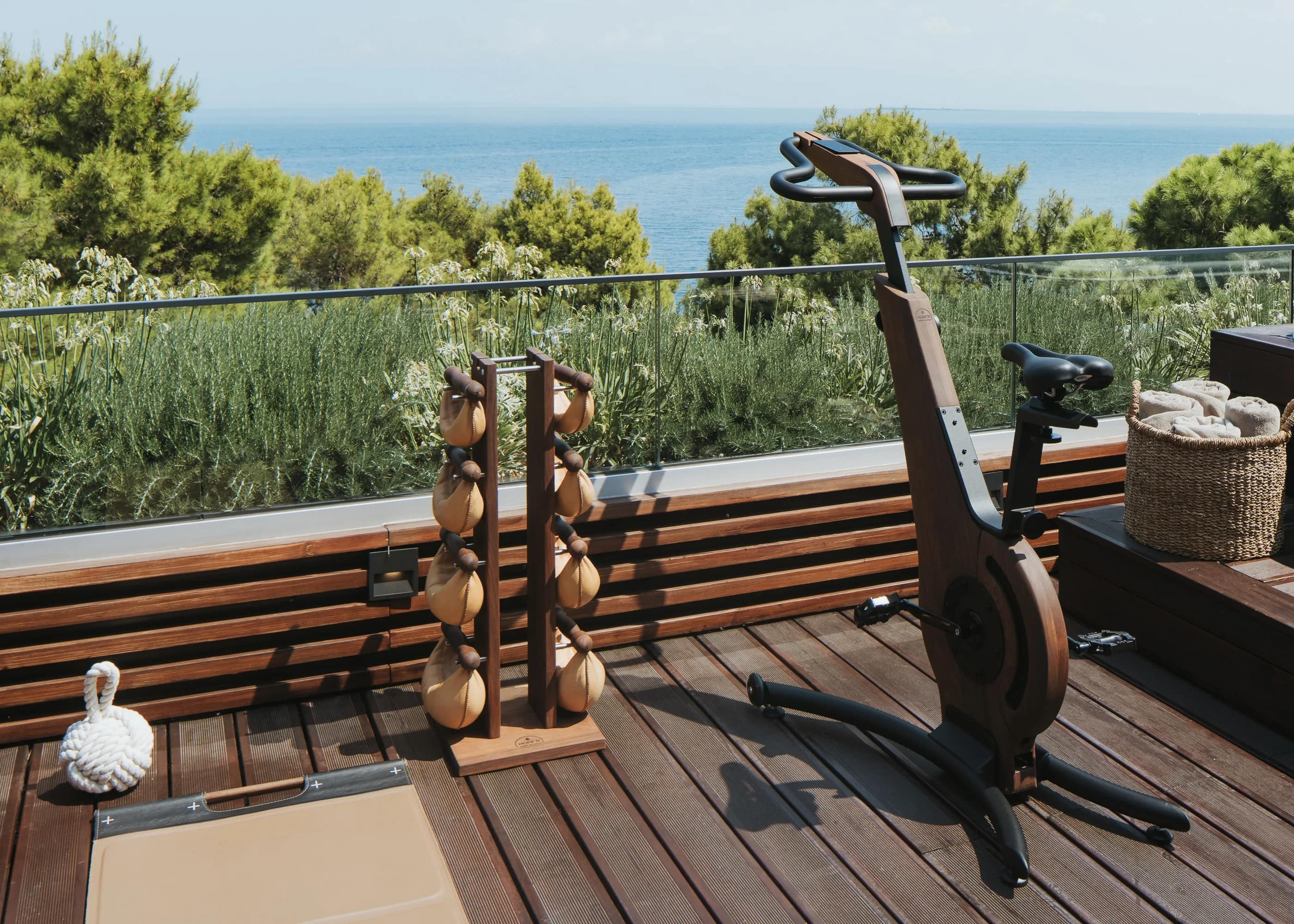 The deck gym — kettlebells and the bike, facing the water