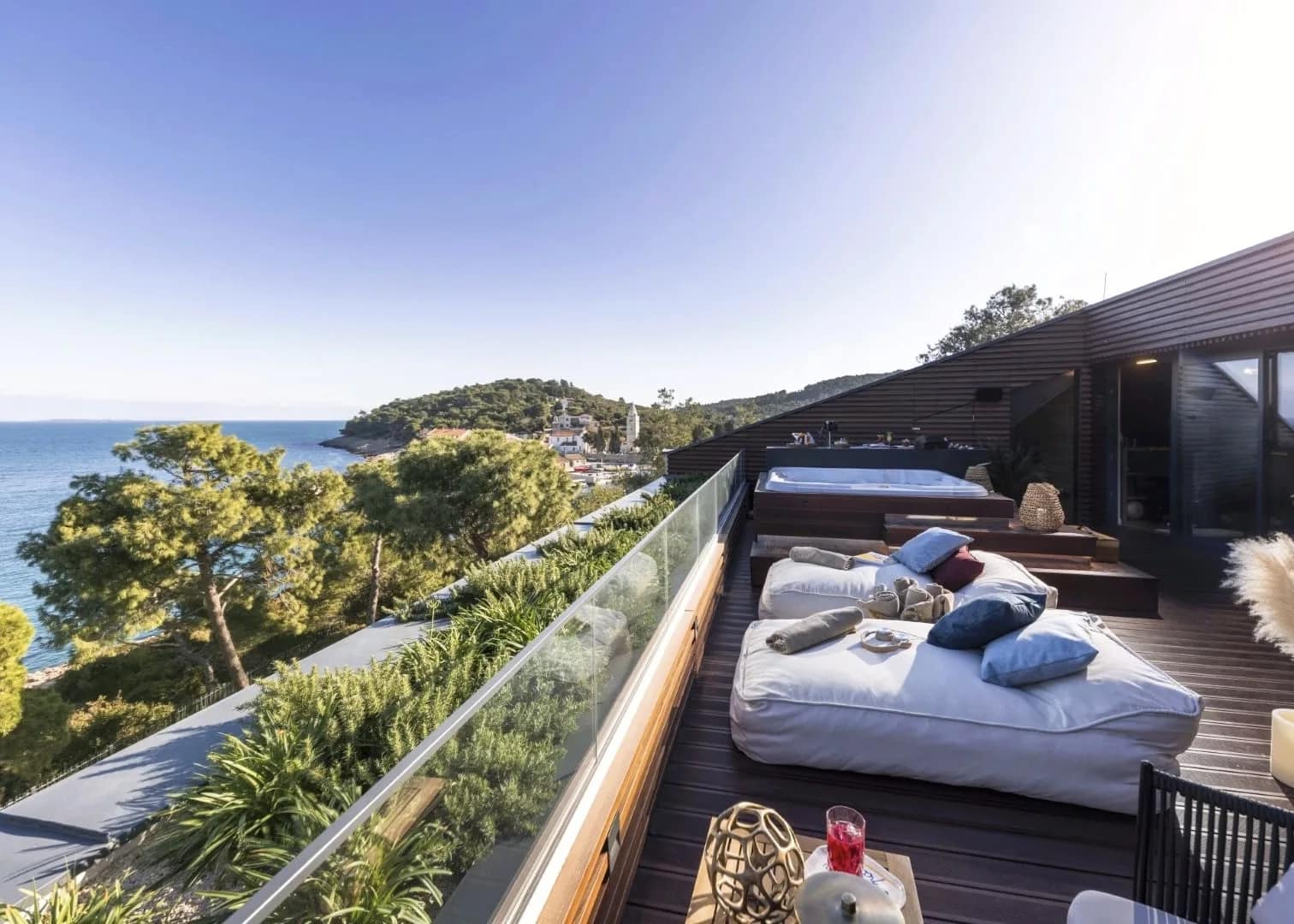 The rooftop terrace — daybeds and the jacuzzi above the cove