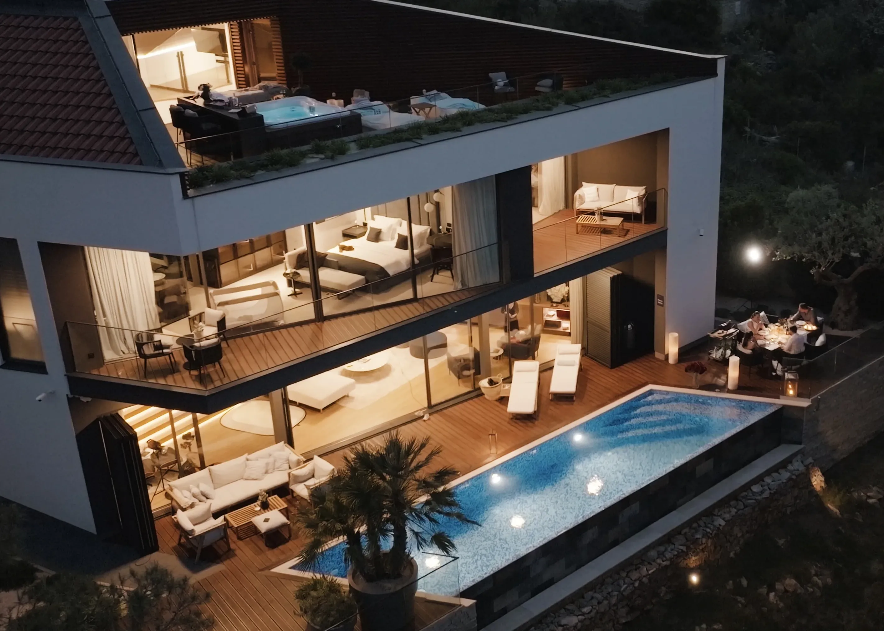 The villa at night, across the lit pool