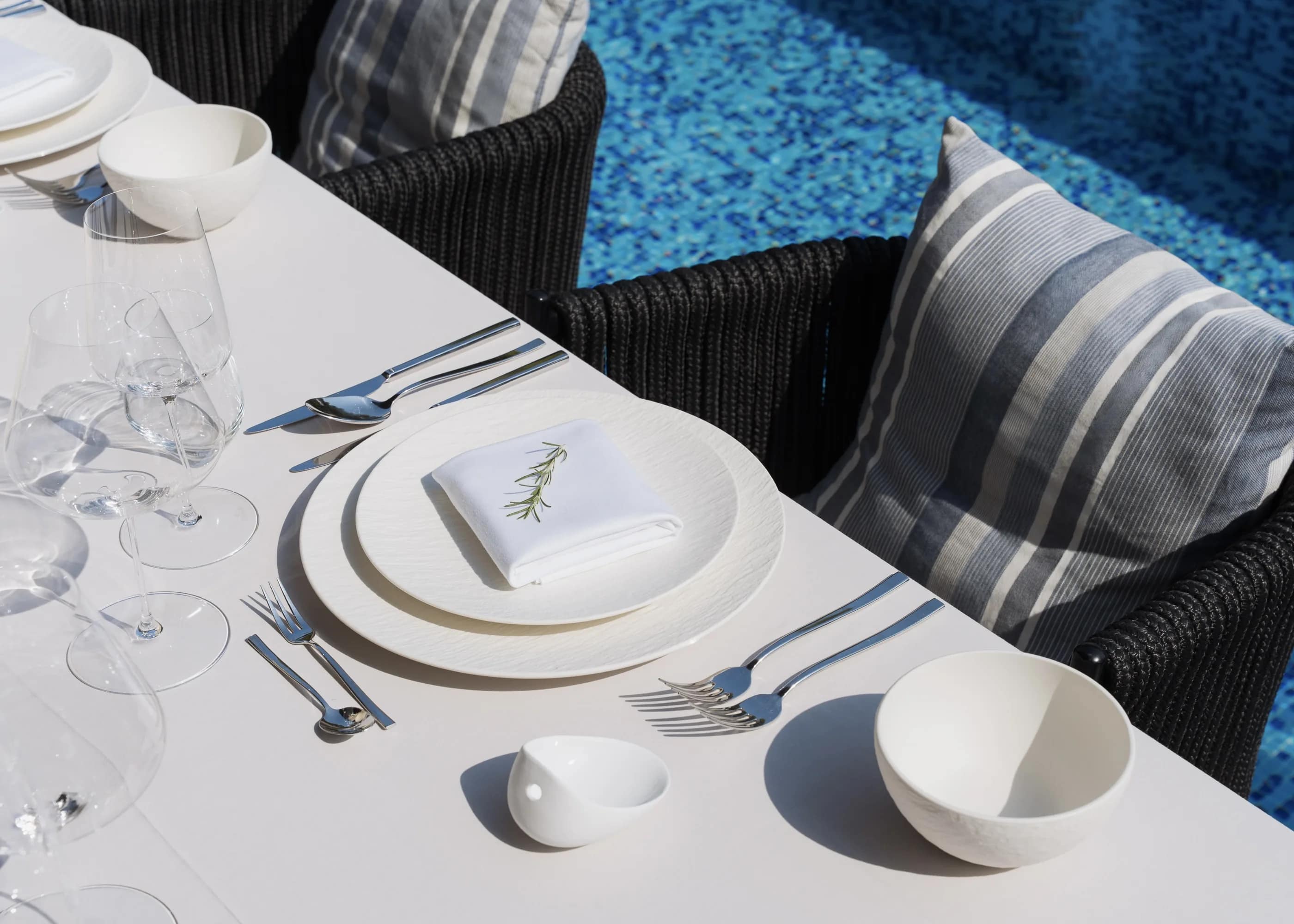 A place setting by the pool, dressed with a sprig of rosemary
