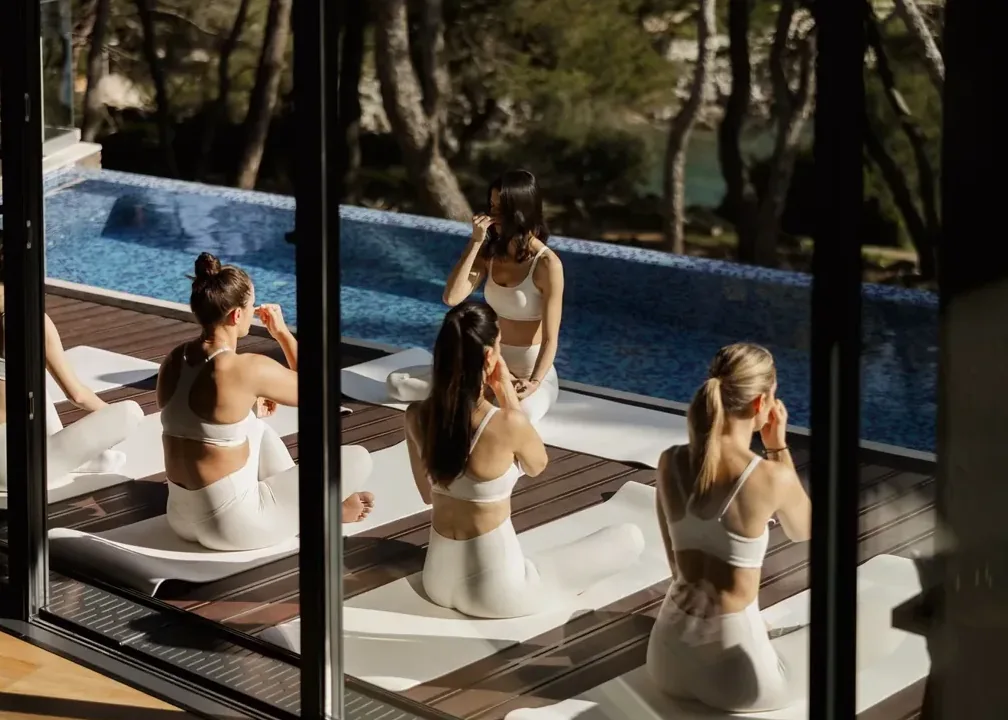 A yoga class, seen through the glass to the pool