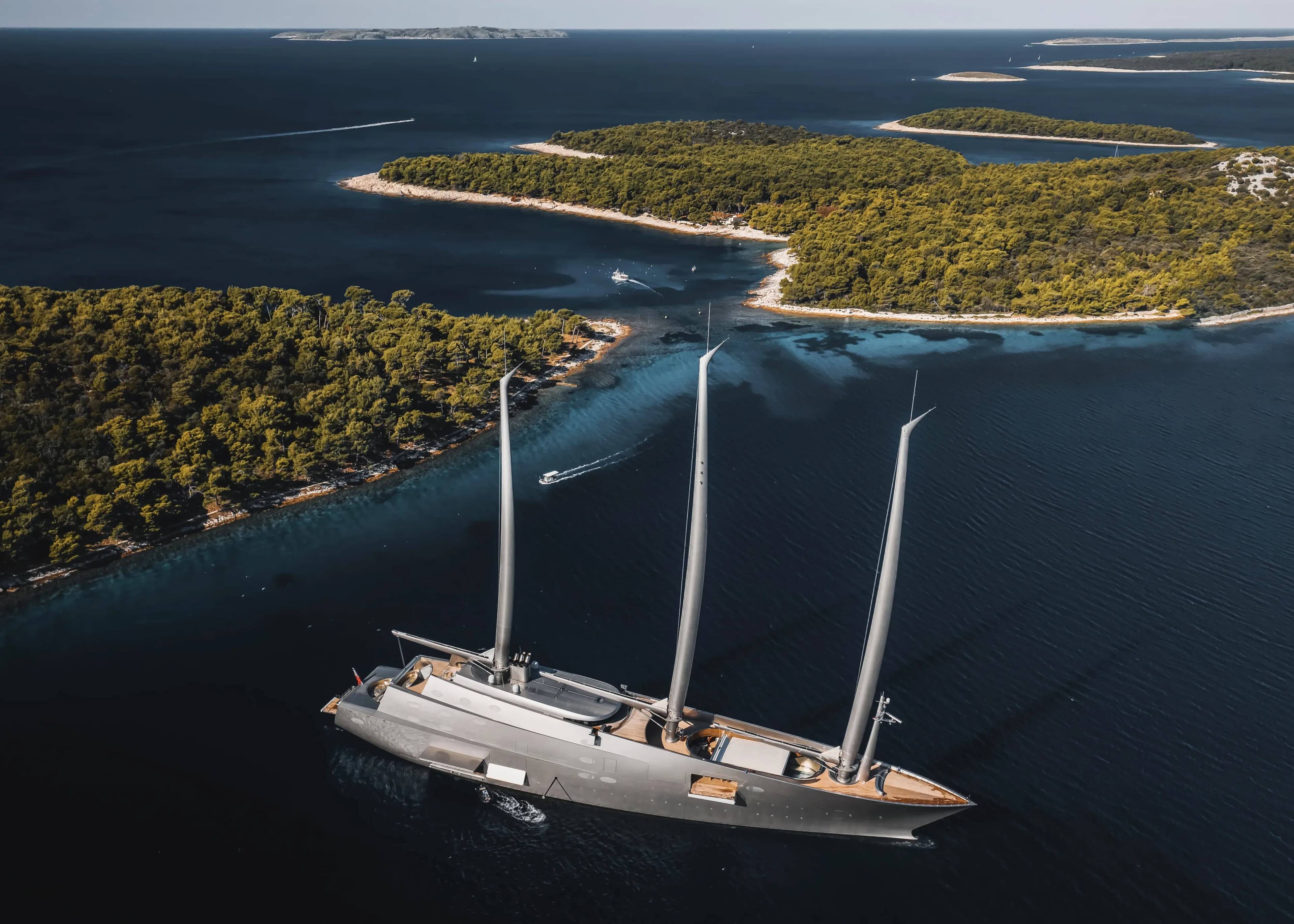 Aerial of a sailing yacht near a pine-covered island