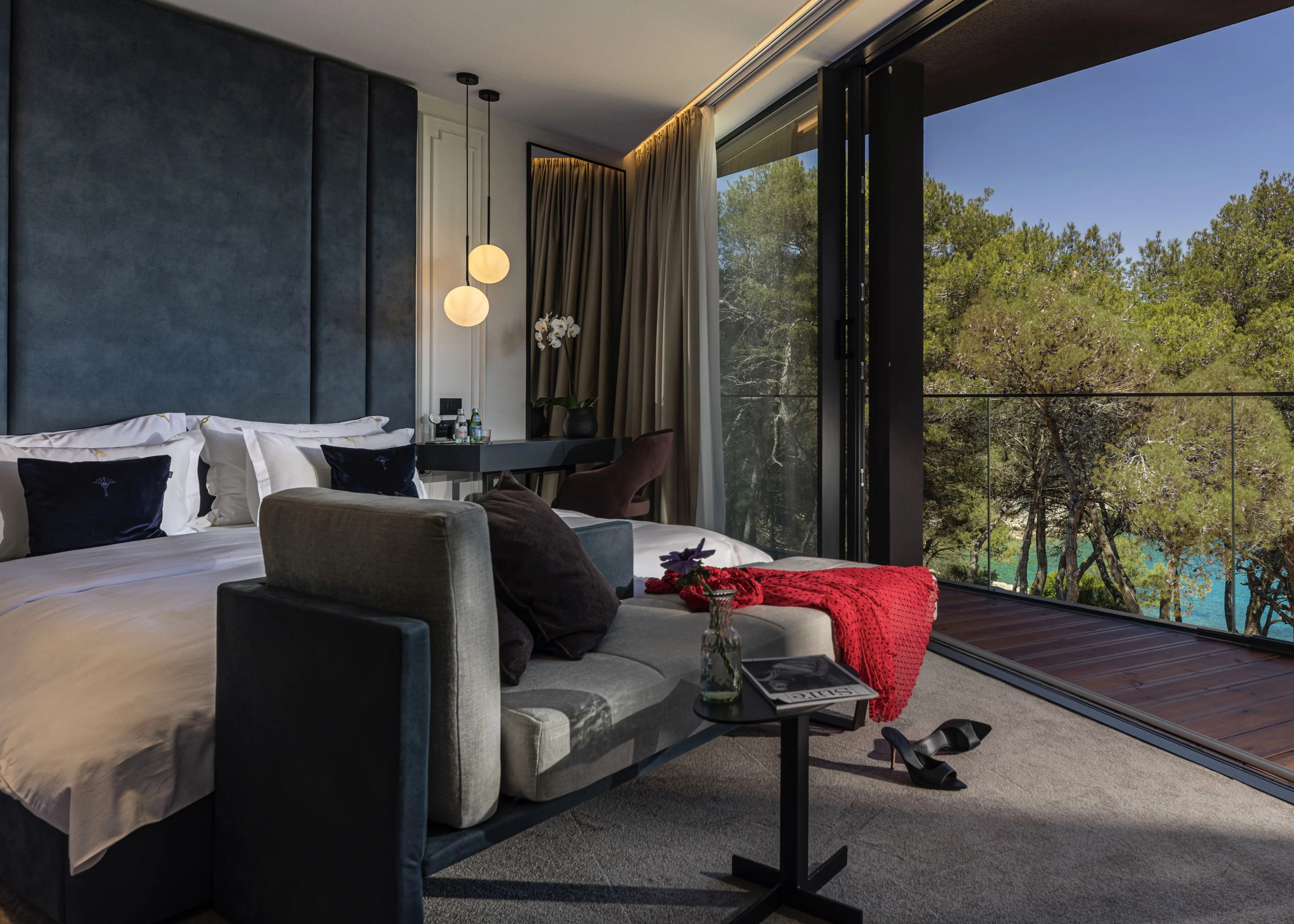 Aldebrand suite at dusk — a red dress and heels left on the daybed, the cove through the open doors