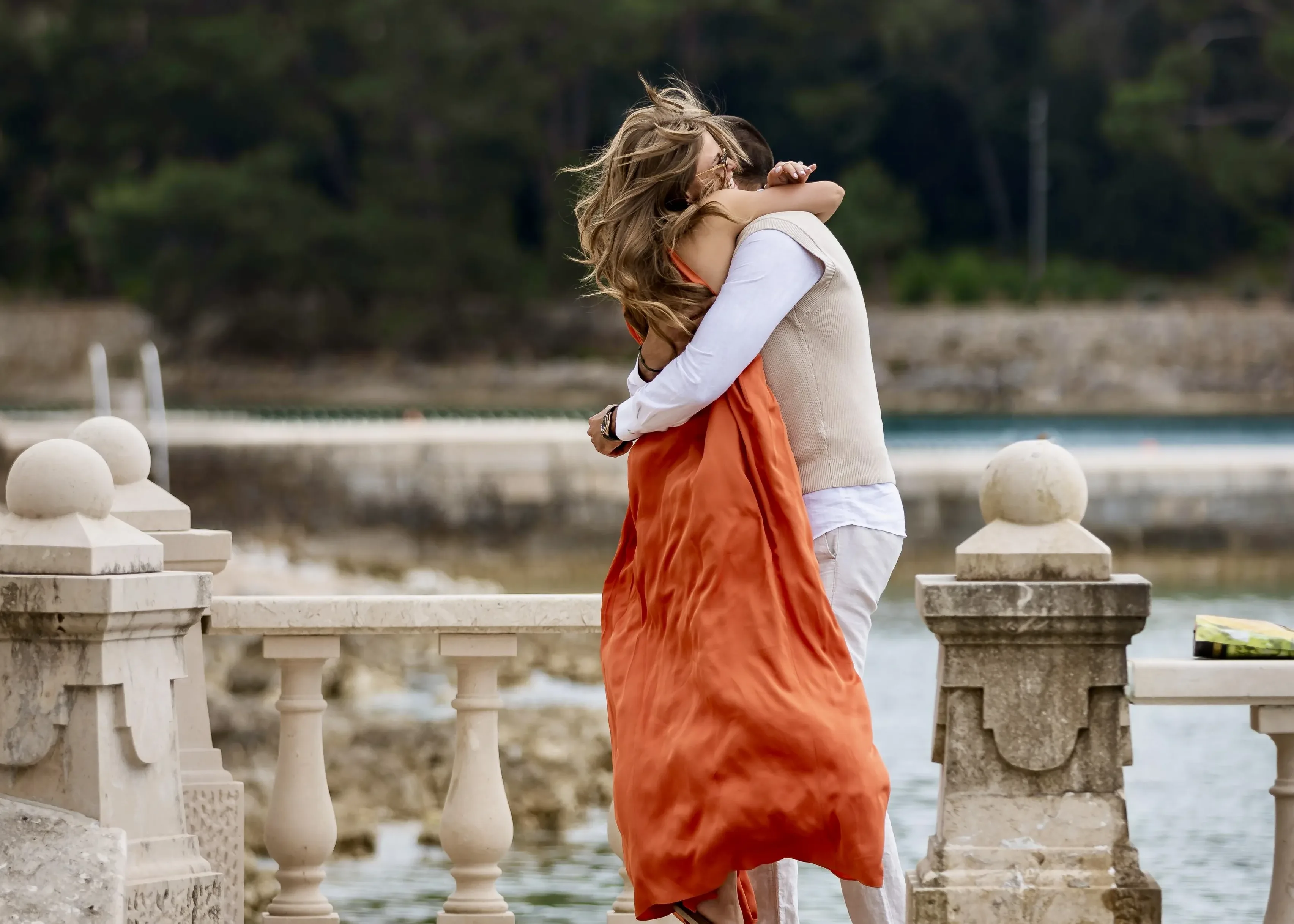 A couple embracing on the stone balustrade above the sea