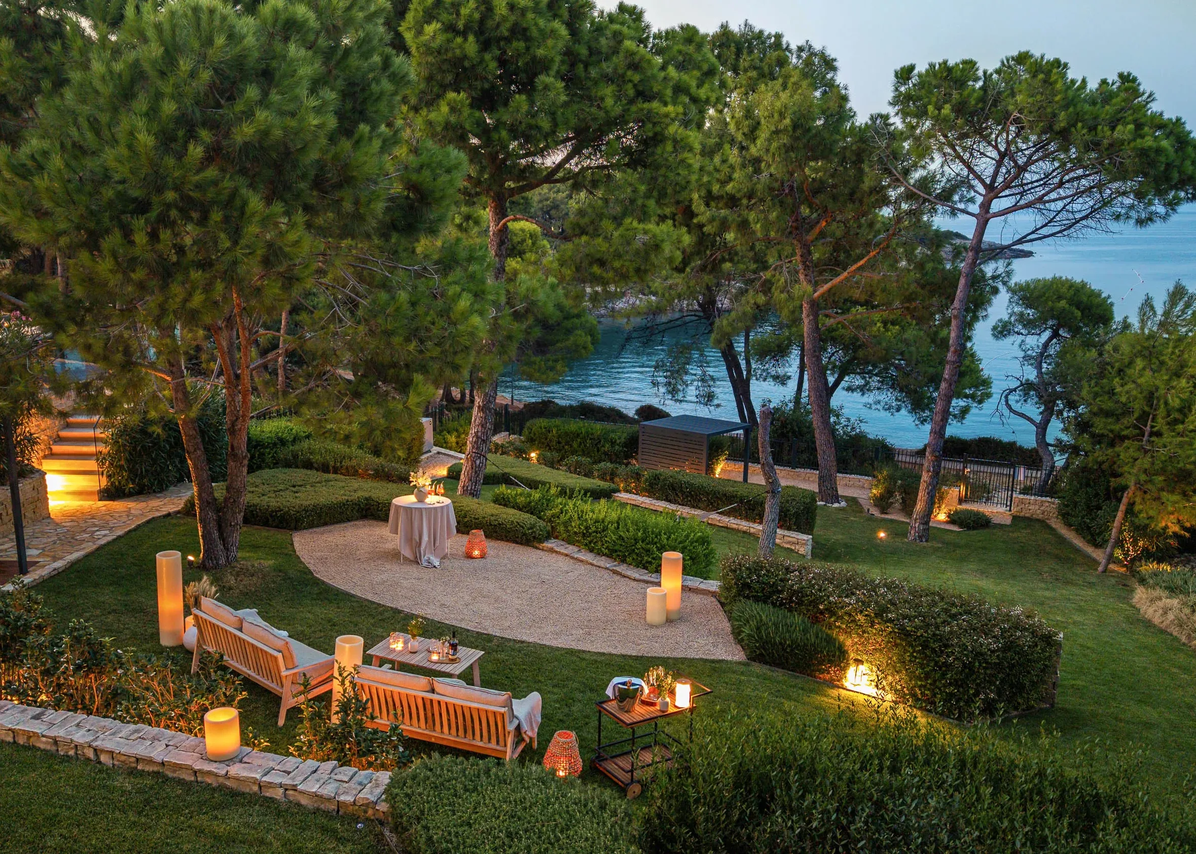 A private dinner setup in the garden among the pines at dusk