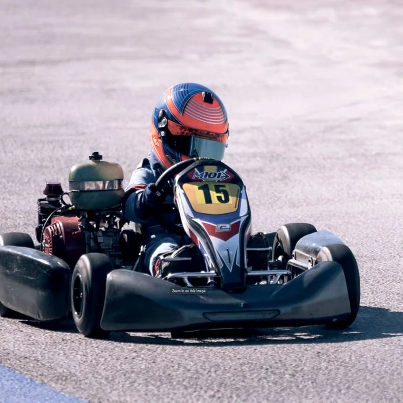 A young go-kart driver cornering on the track