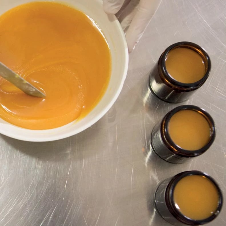 Three amber jars of homemade salve next to a mixing bowl