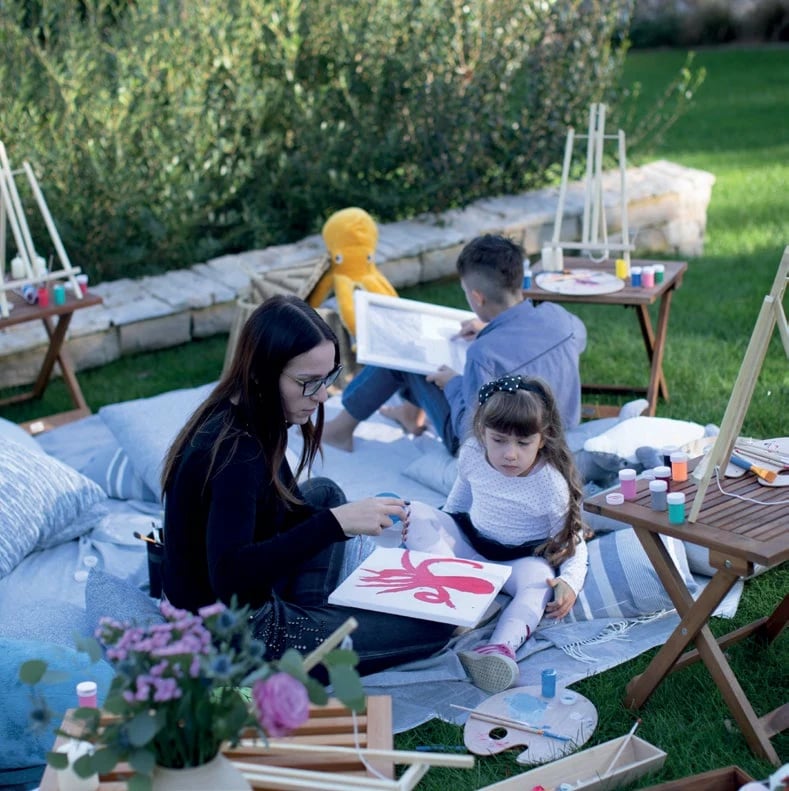 A mother and daughter painting an octopus on easels in the garden