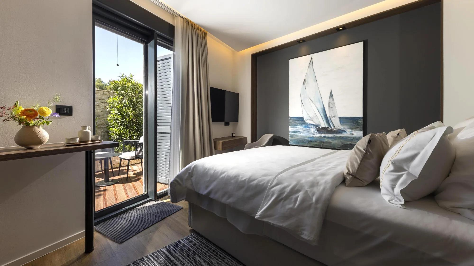 St. Martin Suite — the bed beneath the sailboat canvas, the private terrace through the sliding glass
