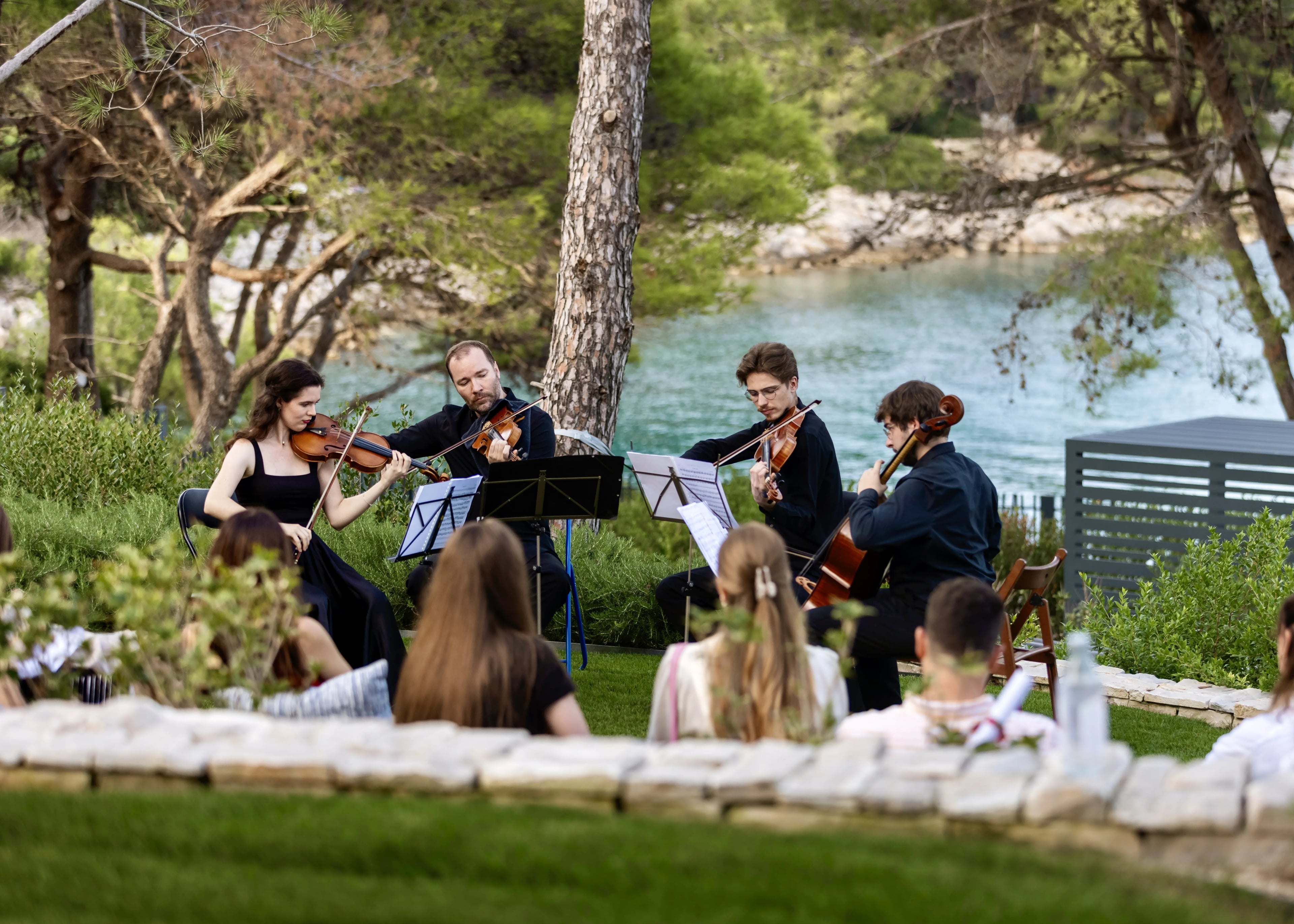 A string quartet performing outdoors in the villa garden by the cove