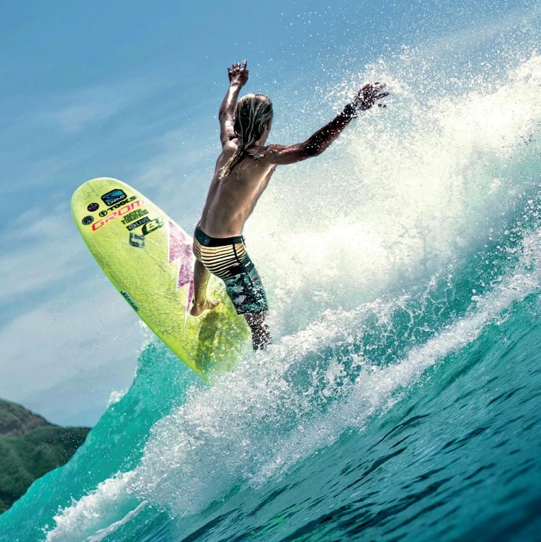 A surfer carving across a turquoise wave