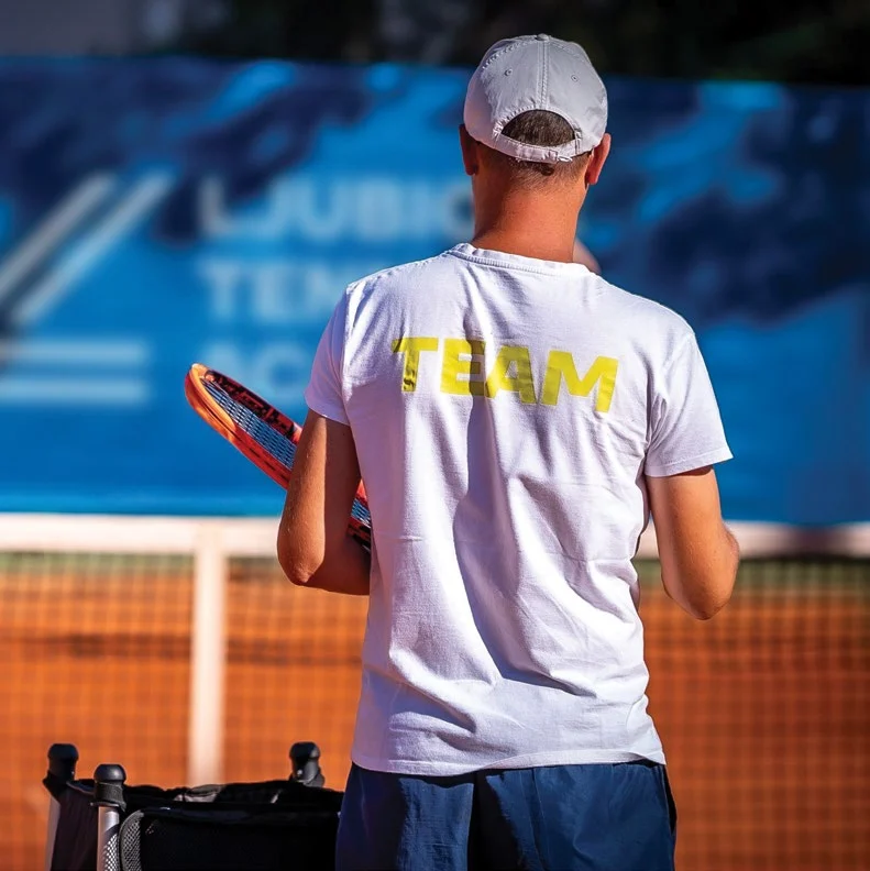 A tennis player on a clay court at the Ljubicic Academy, racket in hand