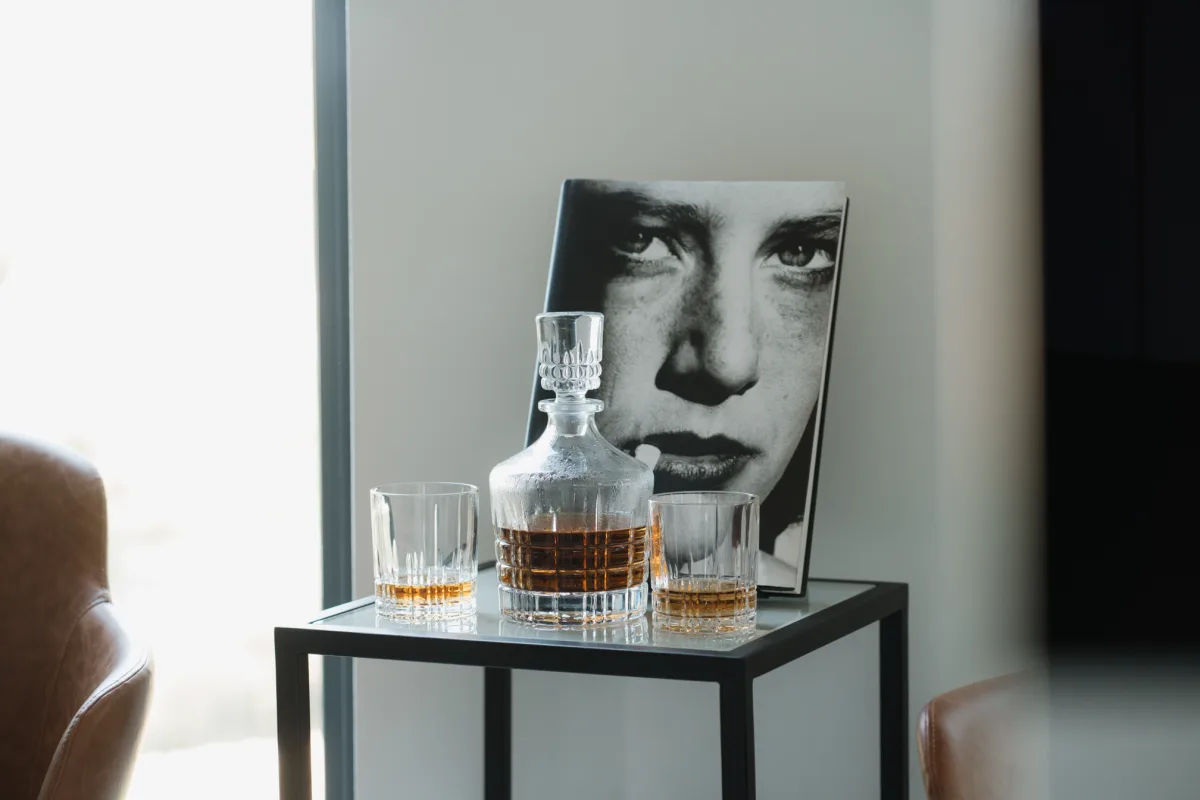 Tesla office side table — crystal whisky decanter and glasses, photography book leaning behind