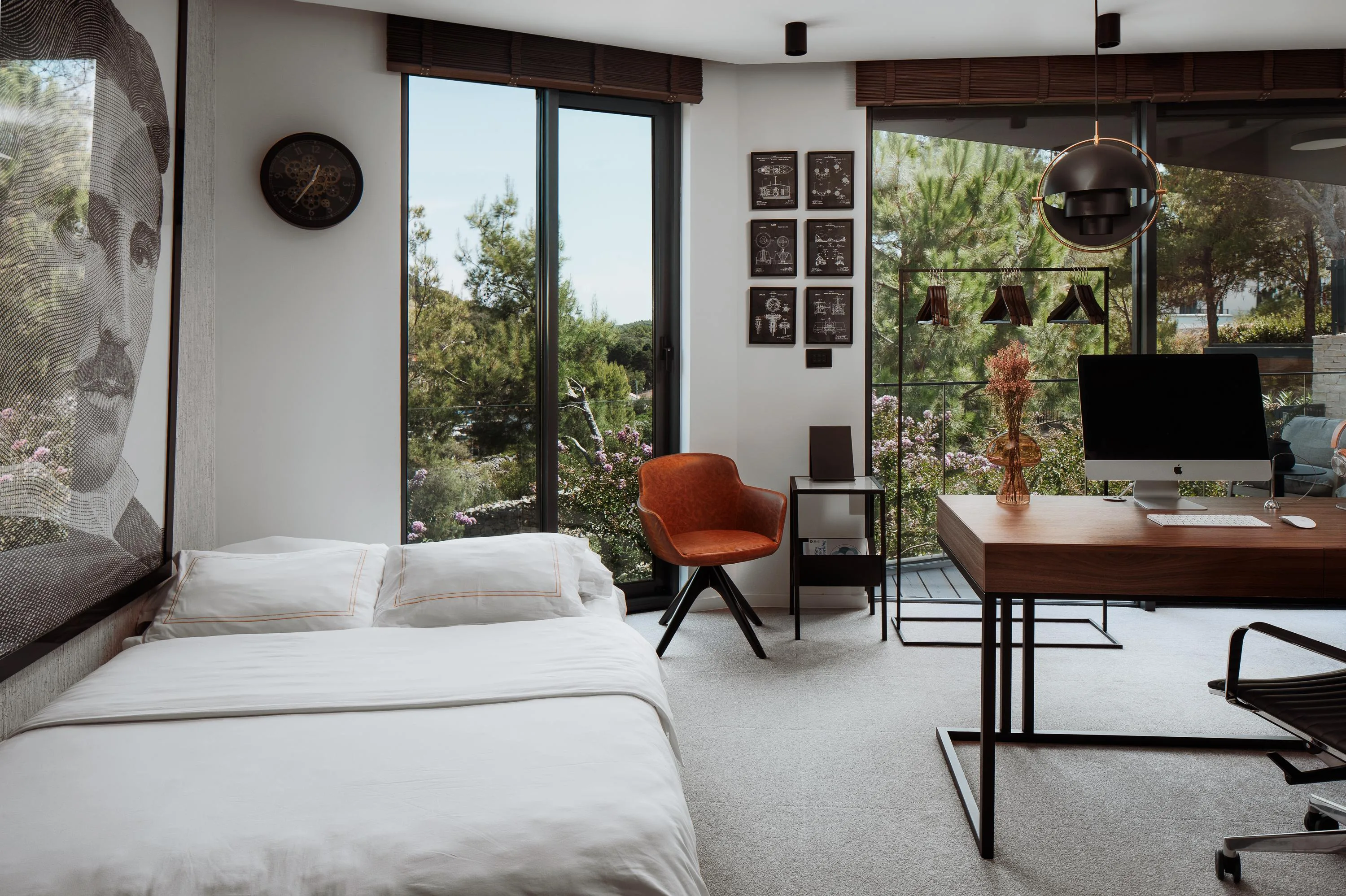 The Tesla suite as a bedroom — the French bed beneath the portrait, the writing desk and patent prints beyond