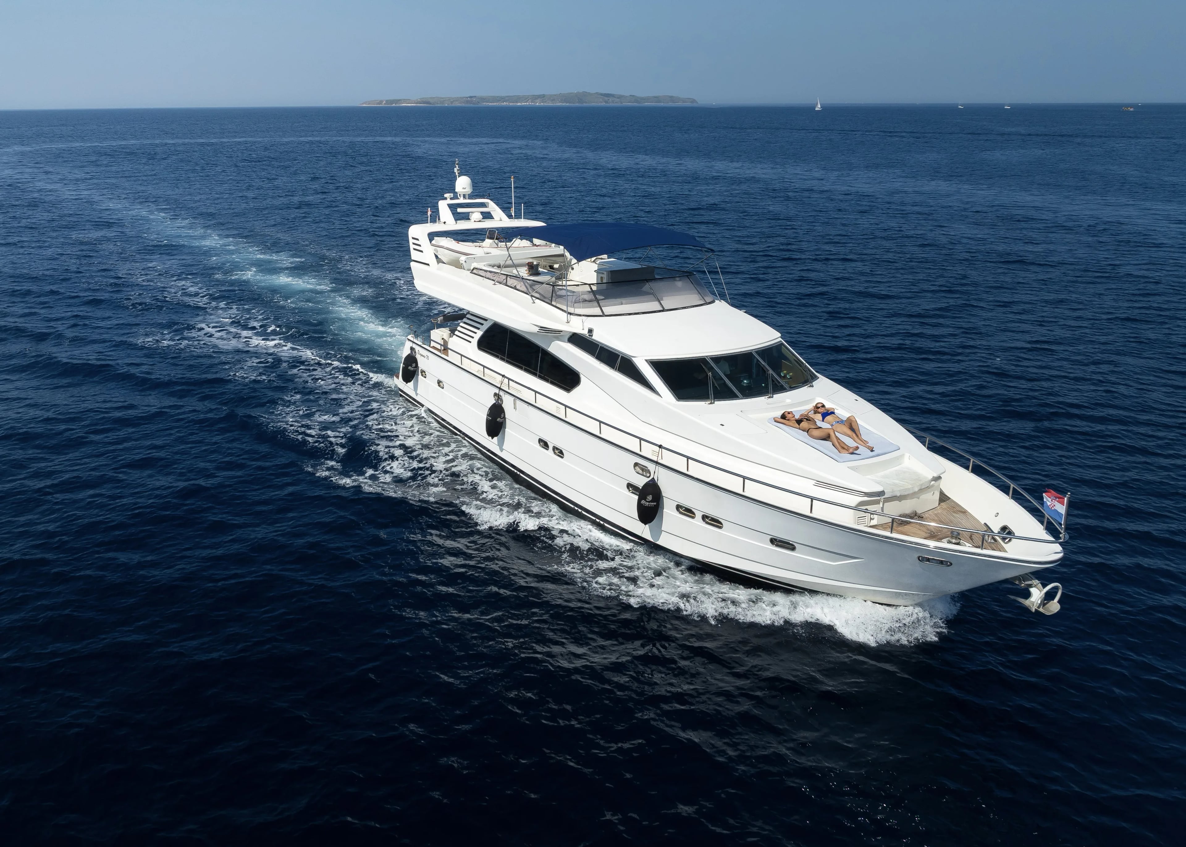 The 22-metre yacht cruising the open sea, a couple sunbathing on the bow